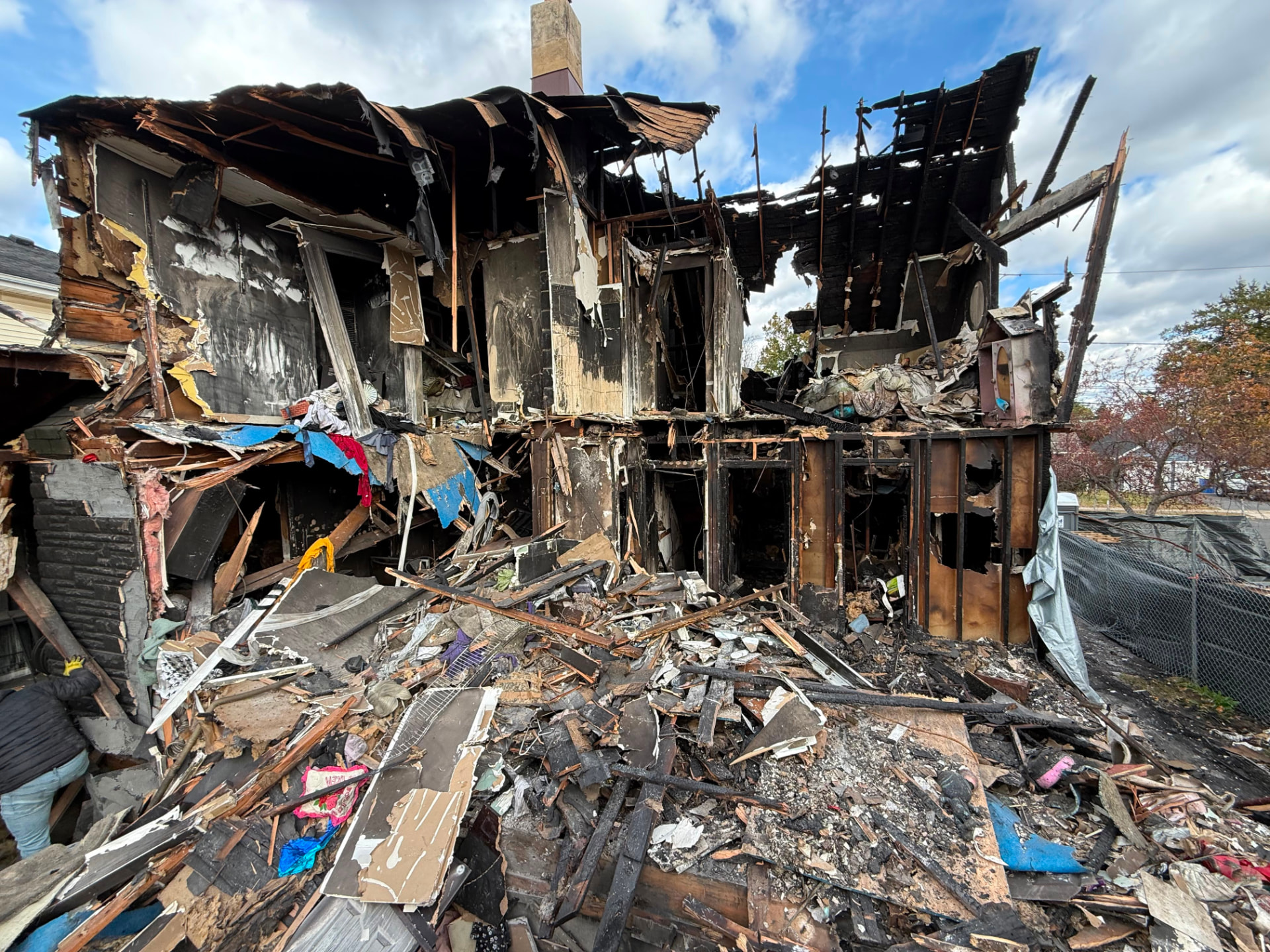 Fire-damaged structure showing collapsed roof rafters, blackened studs and scorched interior walls
